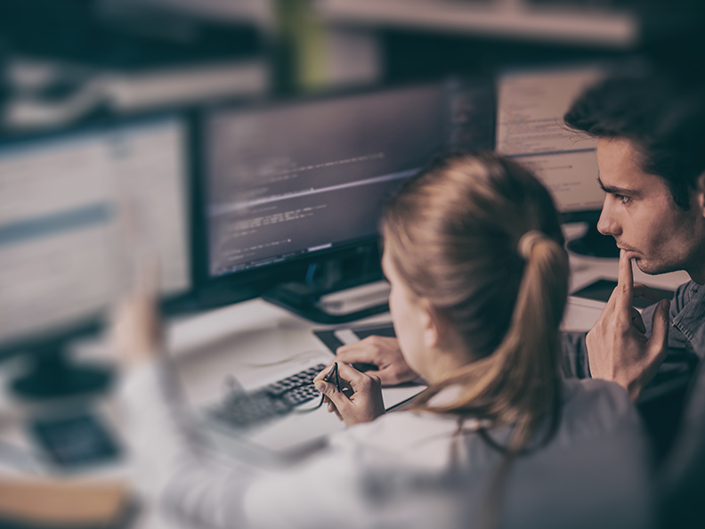 A man and woman review the results of the Unit 42 BEC Readiness Assessment on their computer monitors.